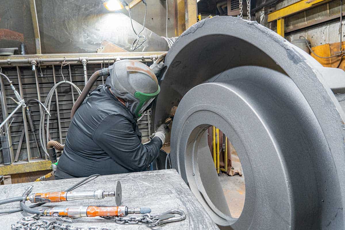 A Badger Foundry Employee Is Working On A Large Circular Iron Product In The Factory