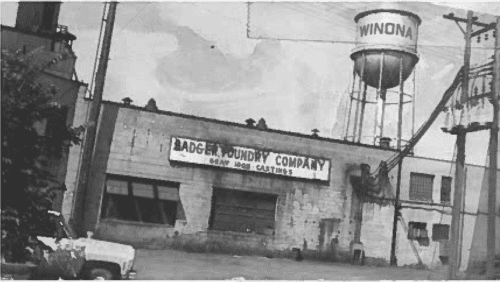 An Old Black And White Photo Of Badger Foundry Company In Front Of The Winona Water Tower.