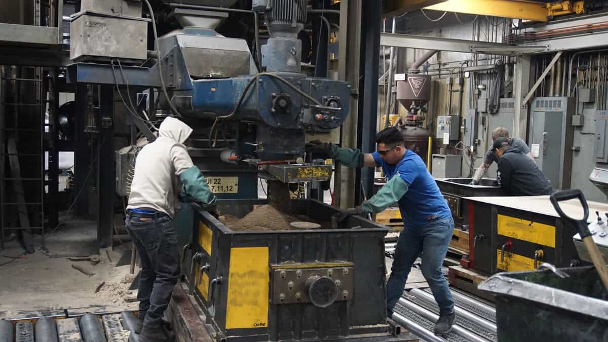 Two Men Working In A Factory With Machinery.
