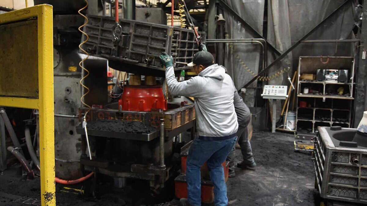 Two Badger Foundry Employees Working On The Factory Floor.